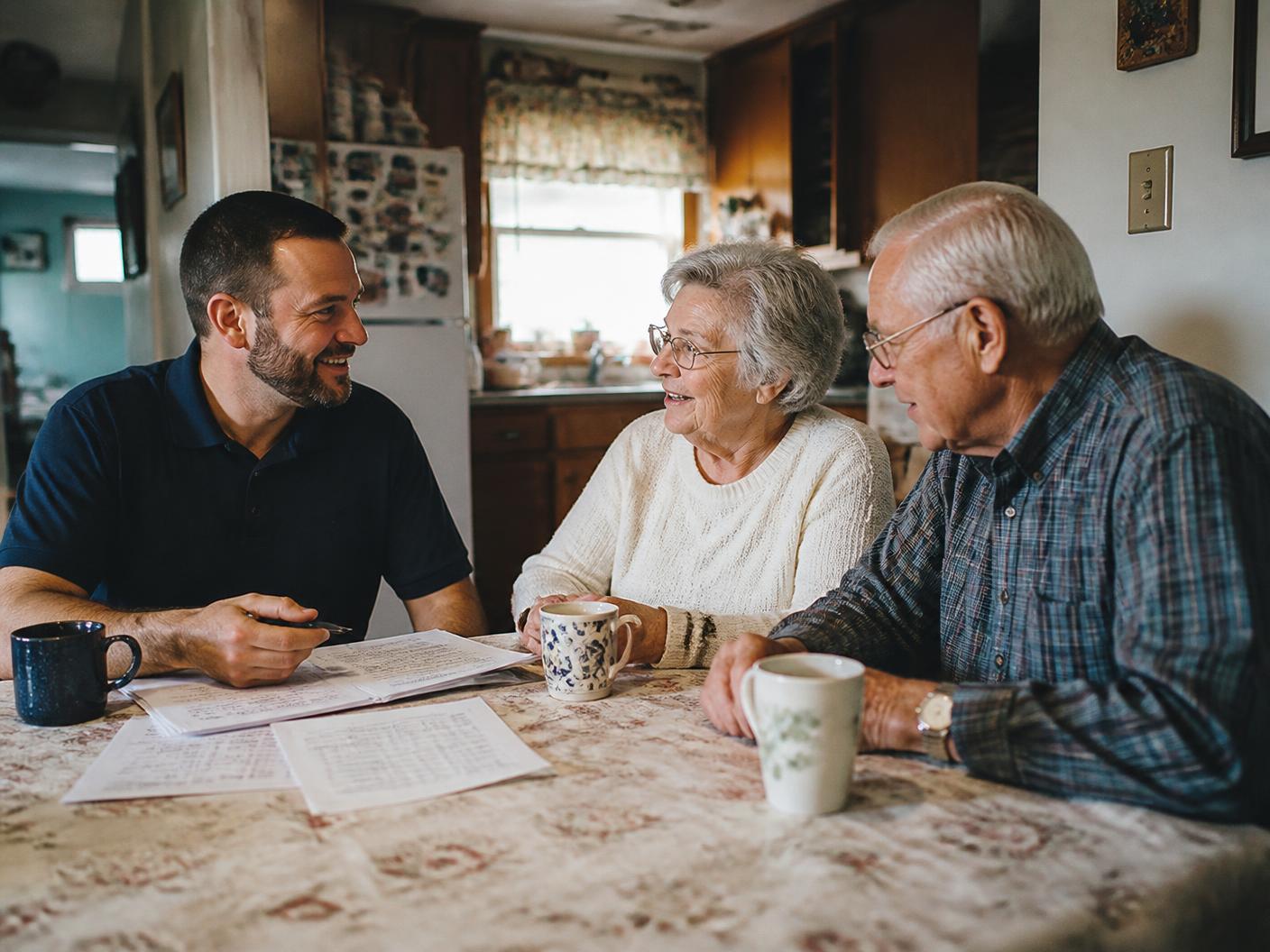 A Handled specialist sitting at the kitchen table with an older couple, going over their home plan